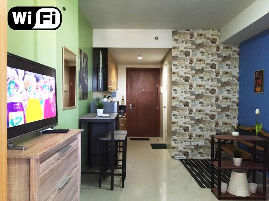 uma sala de estar com uma televisão e uma cozinha em Best Deal NEAREST to MOA, BIGGER 1BR Wifi CableTV em Manila