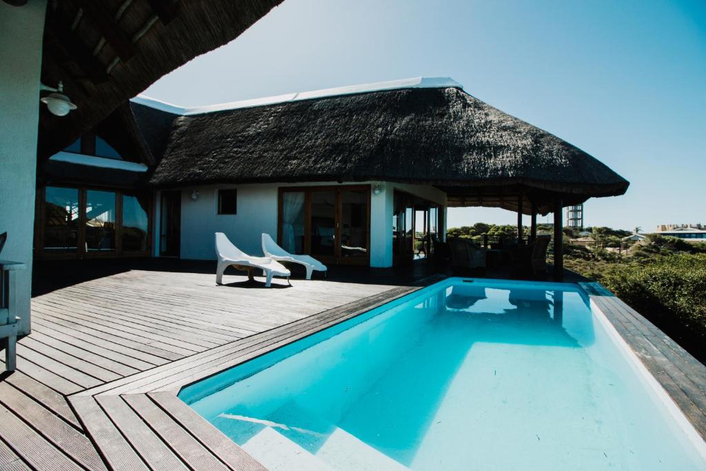 a villa with a swimming pool and a house at Oceans Voice in Jeffreys Bay