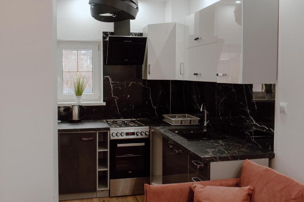 a kitchen with black marble counter tops and white cabinets at Domek przy Parku z basenem Rabka in Rabka