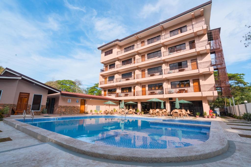 a hotel with a swimming pool in front of a building at Island Wanderers Inn in Coron