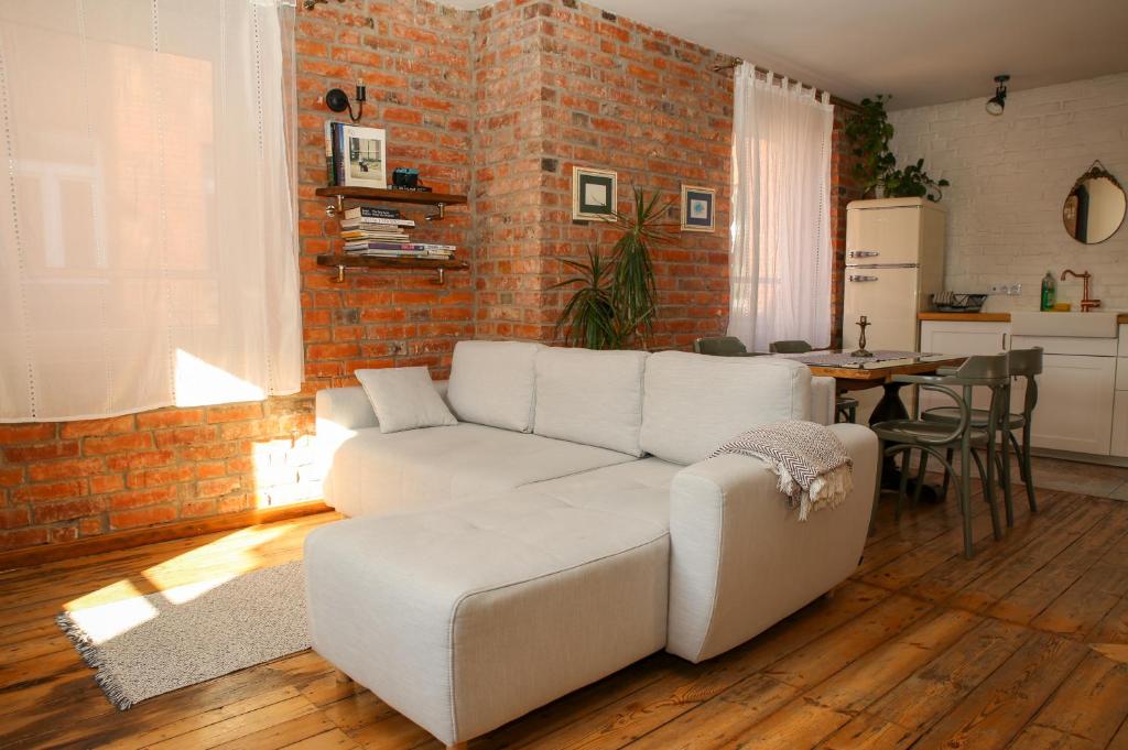 a living room with a white couch and a brick wall at Bralu street apartments in Liepāja