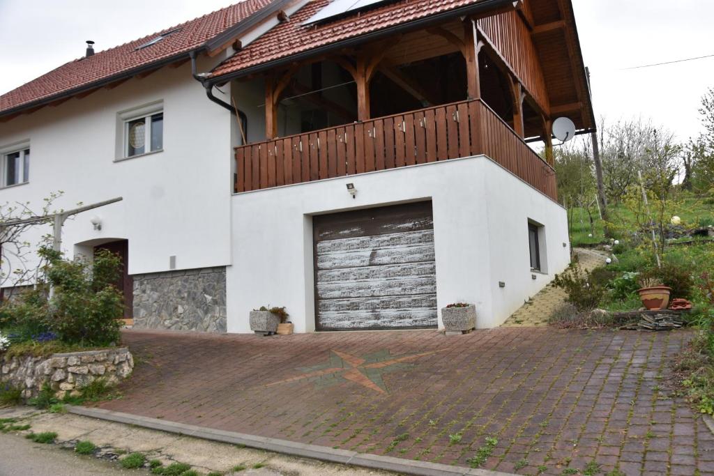 a white house with a garage and a balcony at Apartma Silvia in Metlika