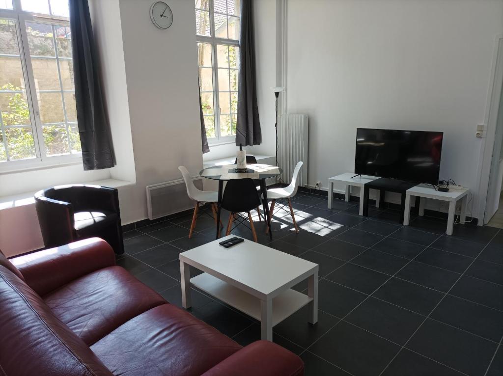 uma sala de estar com um sofá, uma mesa e uma televisão em O'Couvent - Appartement 87 m2 - 4 chambres - A501 em Salins-les-Bains