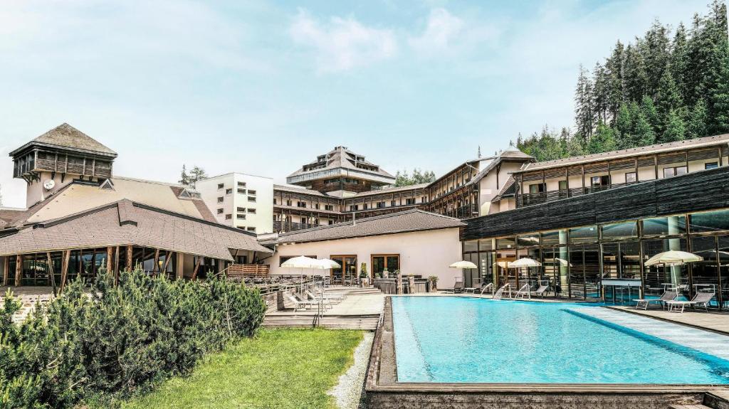 a hotel with a swimming pool in front of a building at Falkensteiner Club Funimation Katschberg in Katschberghöhe