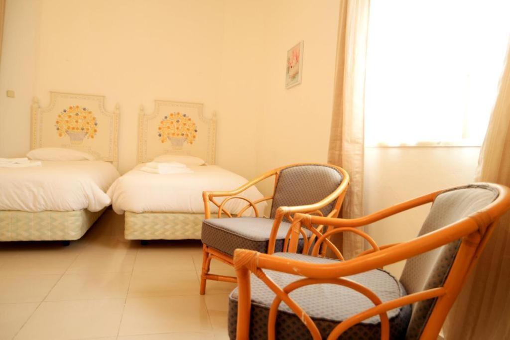 a room with two beds and chairs and a window at Villa Francesa Guest House in Lagos