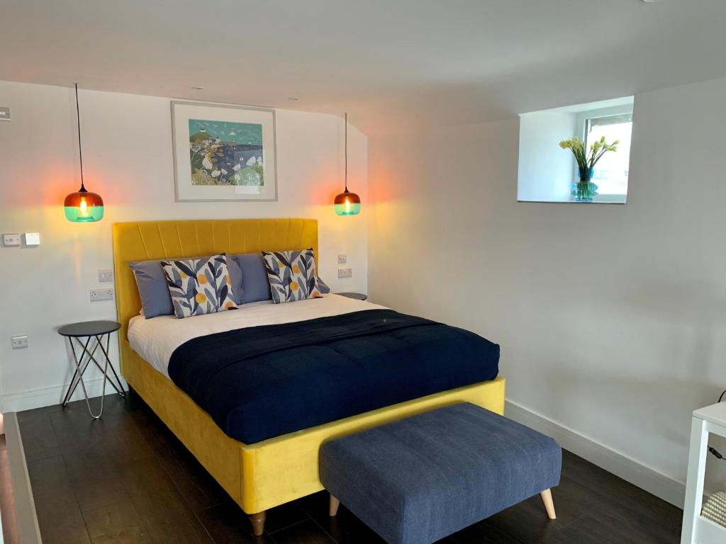 a bedroom with a bed with a yellow headboard and a stool at Modern studio apartment with stunning views! in St Ives
