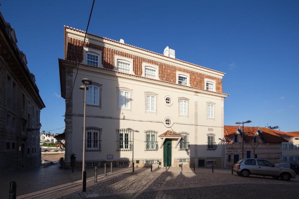 a large white building with a green door on a street at Villa Cascais Boutique Hotel in Cascais