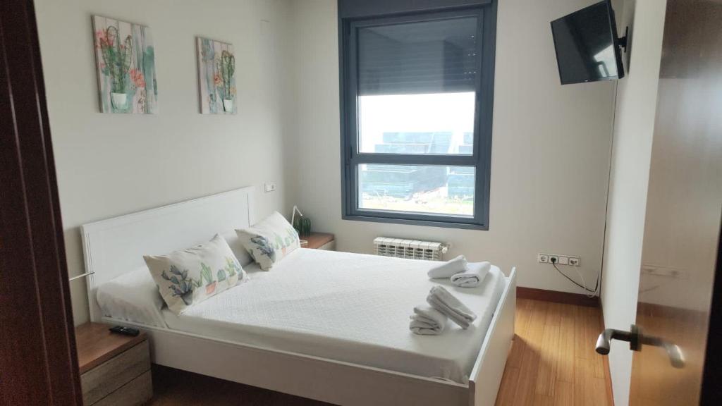 Un pequeño dormitorio con una cama blanca y una ventana en TORRES DE MONTENUÑO, en Oviedo