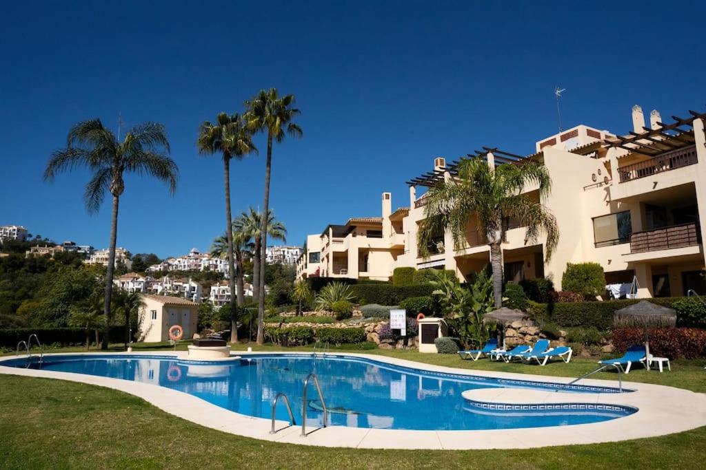 - une piscine en face d'un bâtiment avec des palmiers dans l'établissement Los Piños, 2 Bedroom Apartment with panoramic view, à Benahavís
