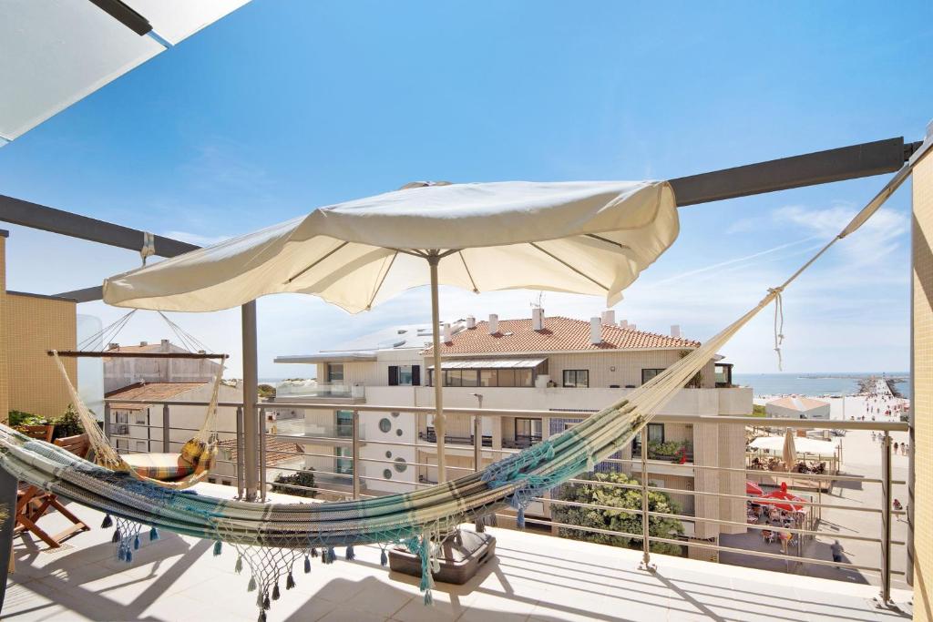 a hammock on a balcony with a view of a building at Cantinho da Praia da Barra in Gafanha da Nazaré