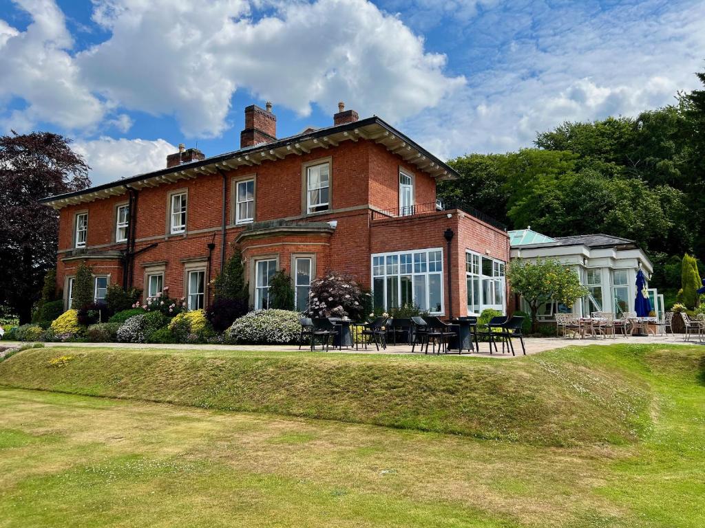 a large brick house with tables and chairs in front of it at The Upper House in Stoke on Trent