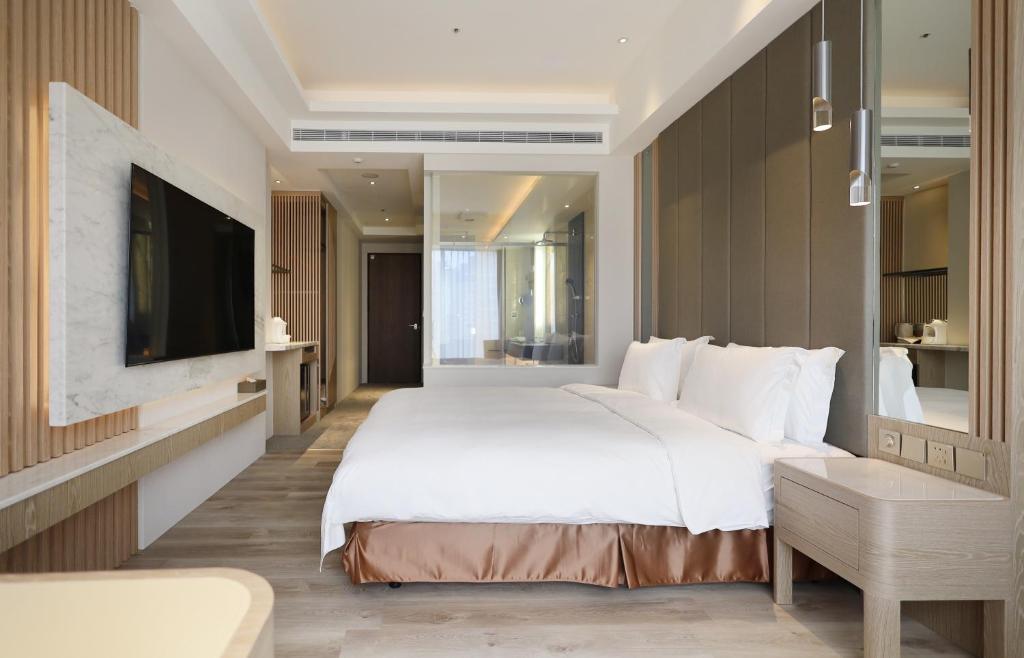 a bedroom with a large white bed and a tv at Gamalan Star Hotel in Jiaoxi