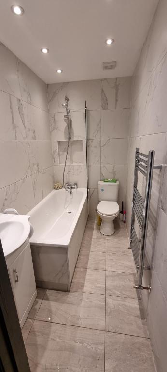 a bathroom with a tub and a toilet and a sink at Modern 2BD Flat in London