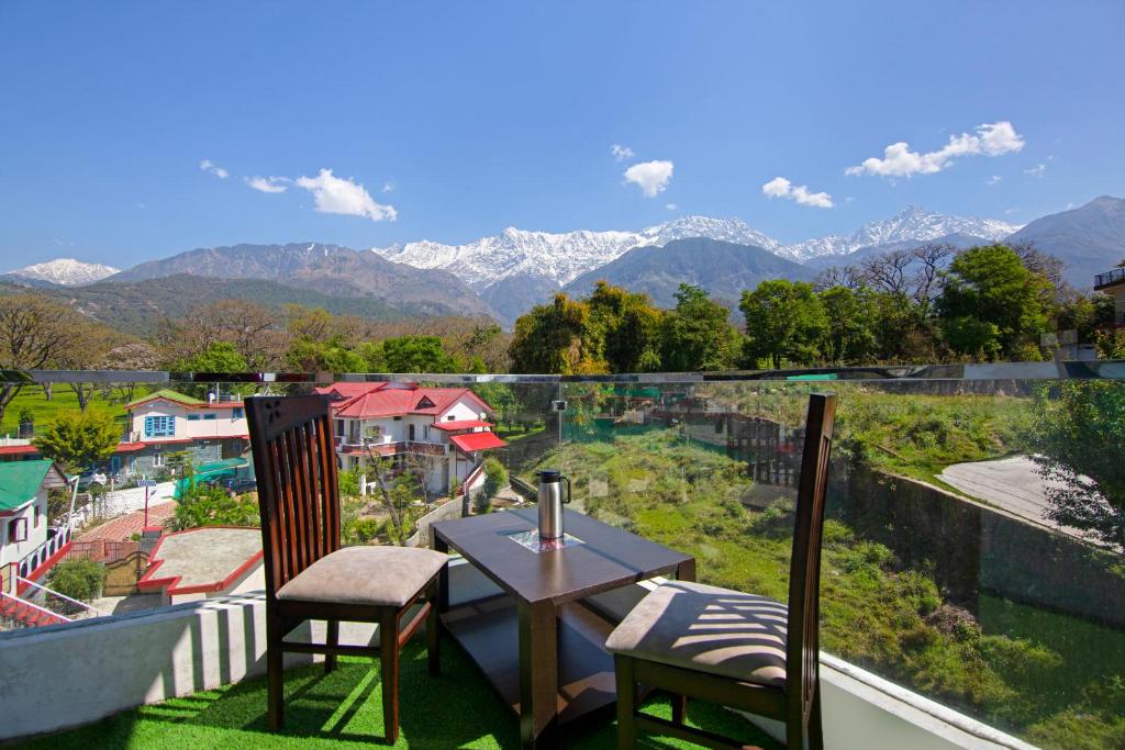 a table and chairs on a balcony with a view of mountains at Treebo Trend Ortus Residency in Dharamshala