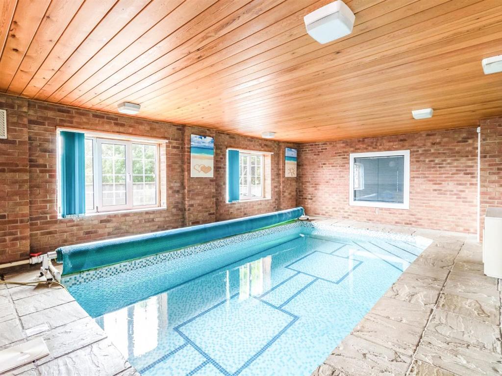 a swimming pool in a room with a wooden ceiling at Northstead Lodge in Flamborough