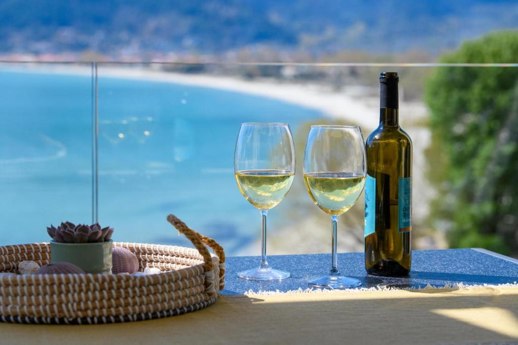 una bottiglia di vino bianco e due bicchieri su un tavolo di Archetypo Luxury Living a Chrisi Ammoudia