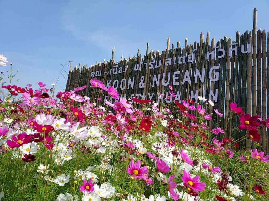 a field of flowers in front of a fence at คูณ-เนื่อง ฟาร์ม สเตย์ หัวหิน Koon & Nueang Farm Stay Hua Hin in Ban Bo Fai