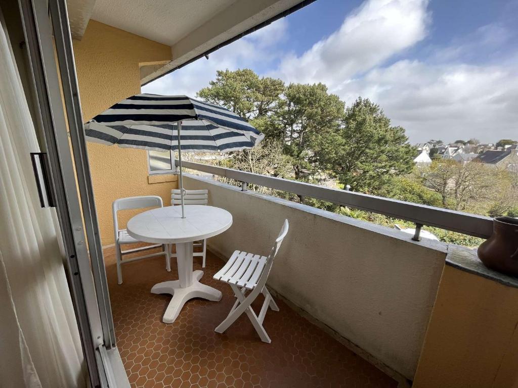 balkon ze stołem, krzesłami i parasolem w obiekcie Studio cosy à Bénodet: plage, restos, thalasso à pied, balcon et parking privé - FR-1-481-135 w mieście Bénodet