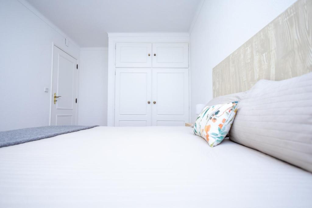 a white bedroom with a large bed with a pillow at Cem Sentido - Alentejo Apartments in Portalegre