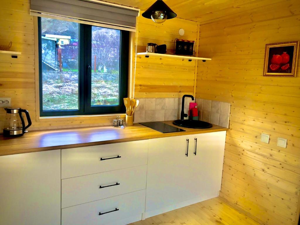 una cocina con armarios blancos y una ventana en Hillside Kazbegi, en Kazbegi