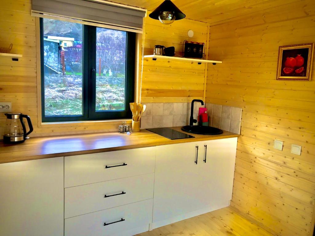 a kitchen with white cabinets and a window at Hillside Kazbegi in Stepantsminda