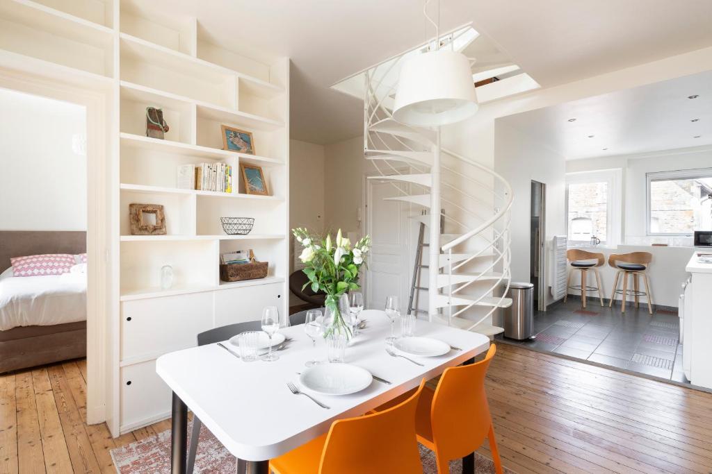a white dining room with a white table and orange chairs at Les Vigies by Cocoonr in Saint Malo