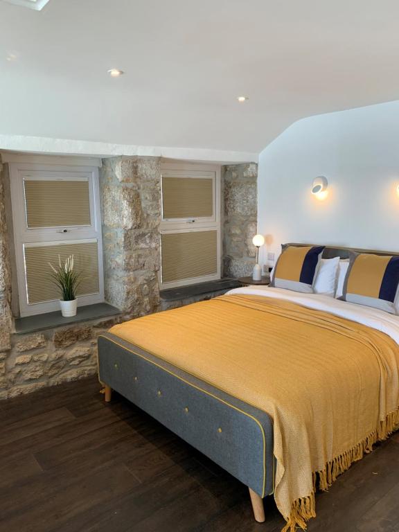 een slaapkamer met een groot bed en 2 ramen bij Beach House Apartment 1 - St. Ives harbour front apartment with stunning views in St Ives