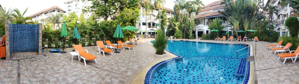 einen Pool mit Stühlen und Sonnenschirmen neben einem Hotel in der Unterkunft Oasis Rentals, Diana Estate, Pattaya in Pattaya