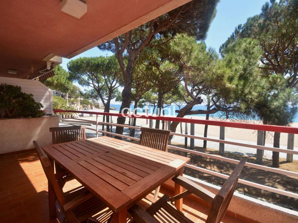 een houten tafel en stoelen op een balkon met uitzicht op het strand bij TAMARIUS 1-4 in Platja  d'Aro