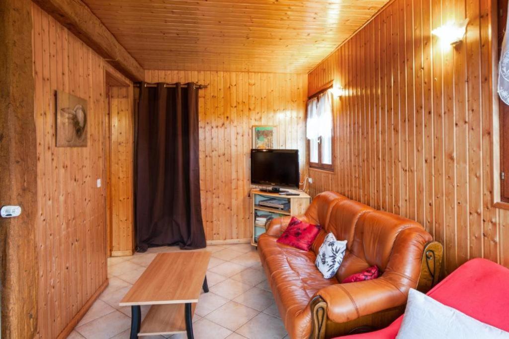 ein Wohnzimmer mit einem Ledersofa und einem TV in der Unterkunft Location Vacances Des 4 Vents in Girmont-Val-dʼAjol