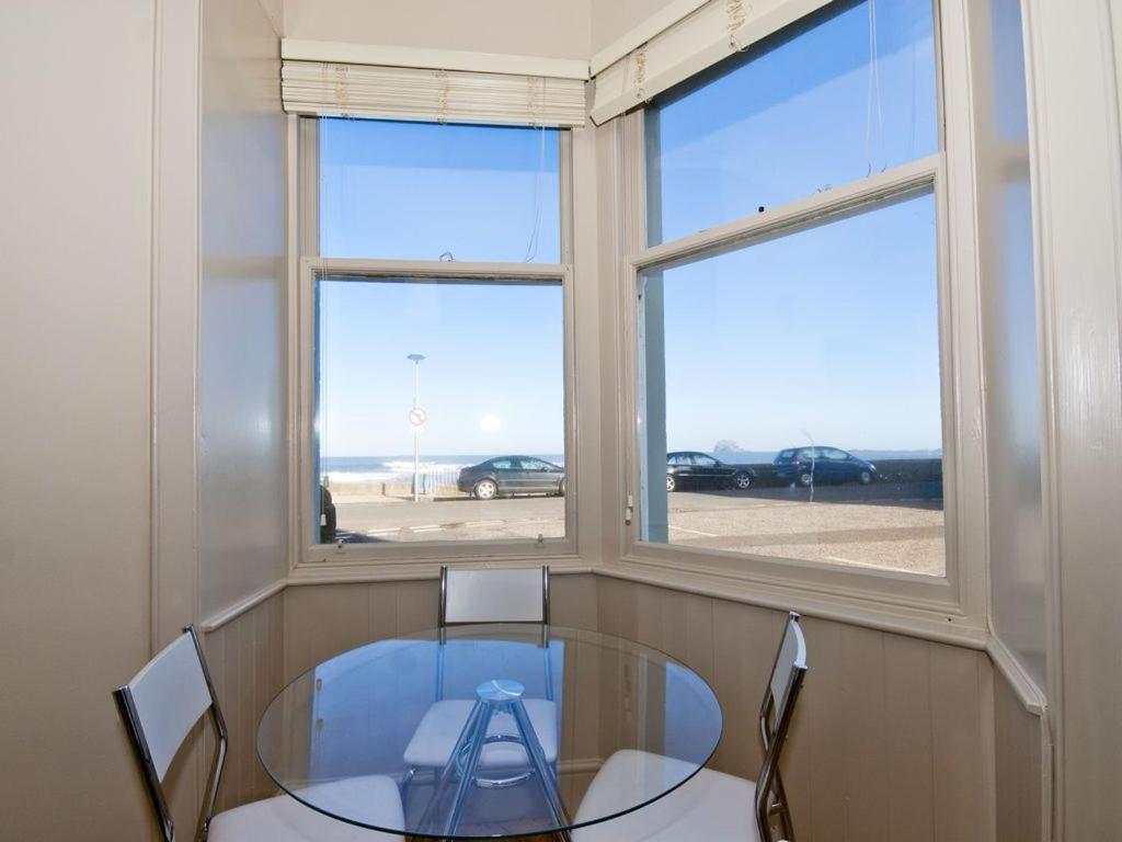 a glass table and chairs in a room with two windows at Seabreeze in North Berwick