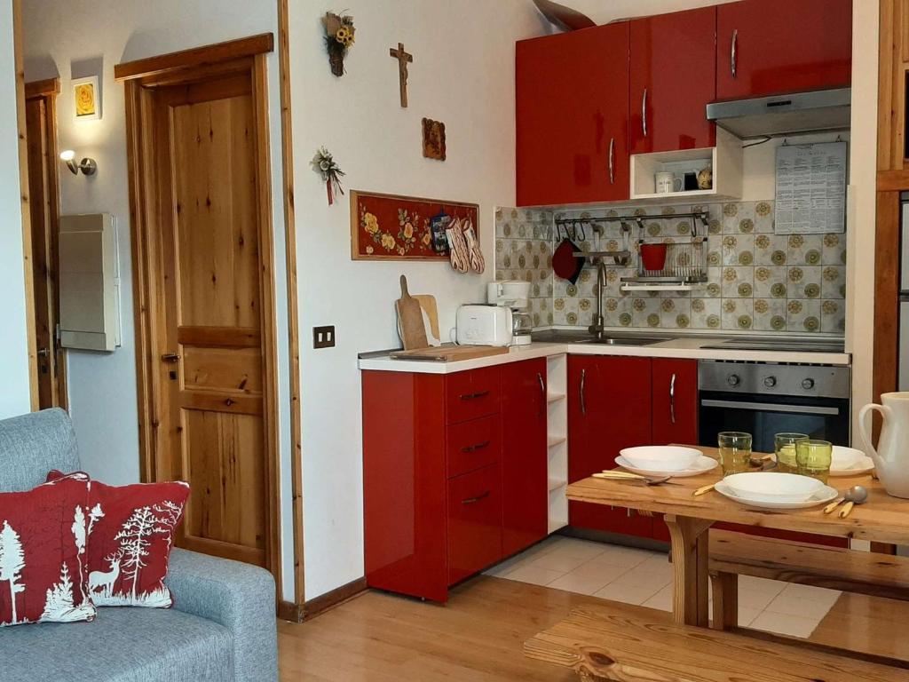 a kitchen with red cabinets and a wooden table at Appartement Montgenèvre, 2 pièces, 5 personnes - FR-1-330D-3 in Montgenèvre