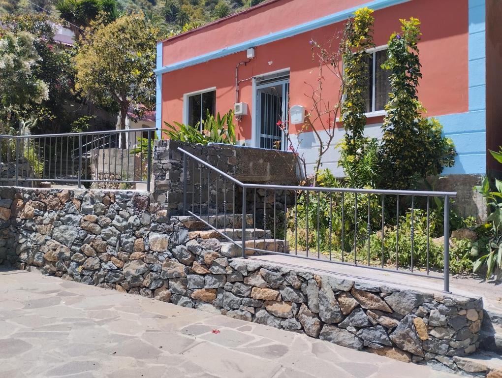 uma casa com uma cerca e uma parede de pedra em Casa Rural Los Chapines em Vallehermoso