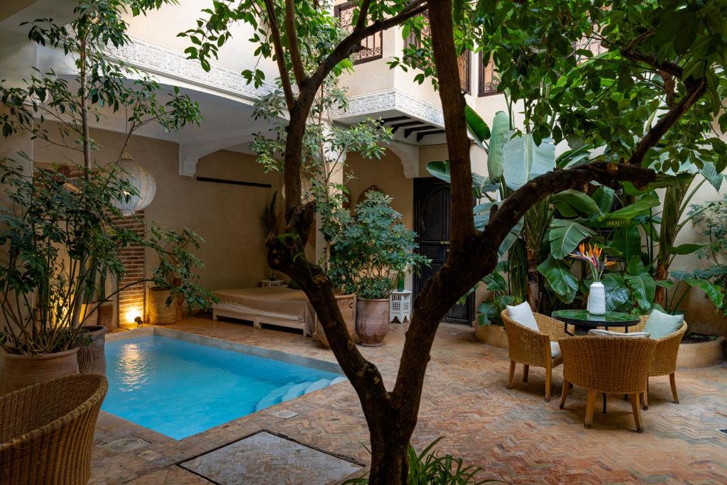 una piscina in un cortile con tavolo e sedie di Riad l'Oiseau du Paradis a Marrakech