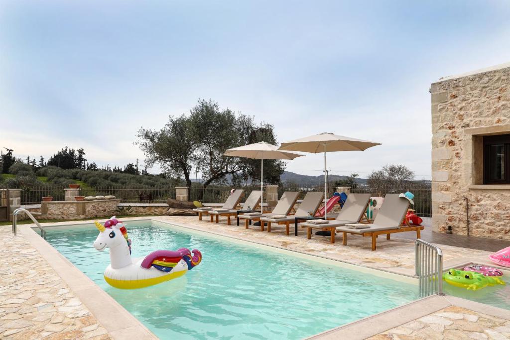 Heliopetra Lux Villa with private Pool في Varípetron: مسبح فيه وحيد القرن والقوارب القابلة للنفخ