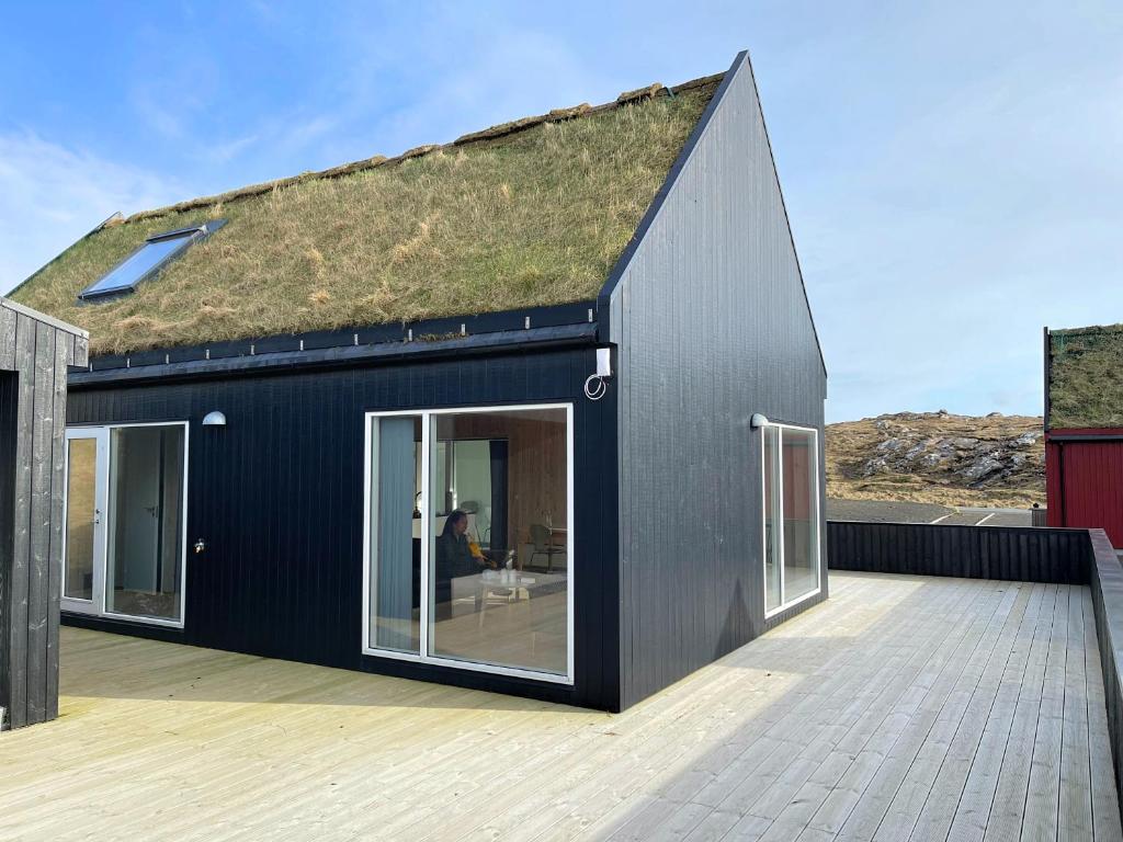 a black house with a grass roof at Captains Cottage in Sandur