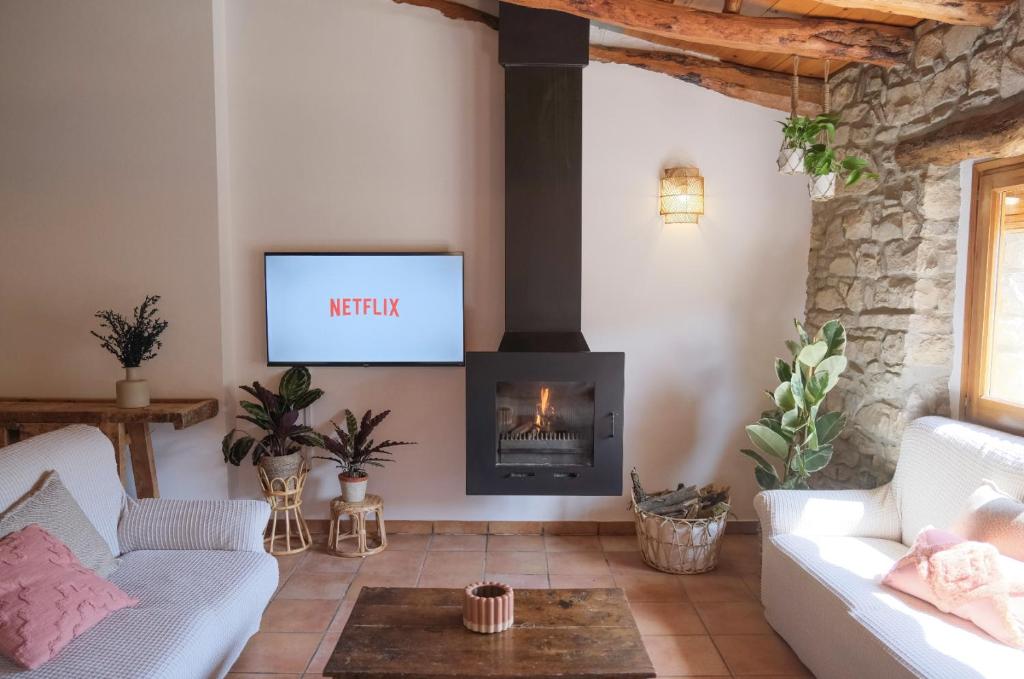 a living room with a fireplace and a tv at Cal Caminer Casa rural con piscina y barbacoa in Guimerá