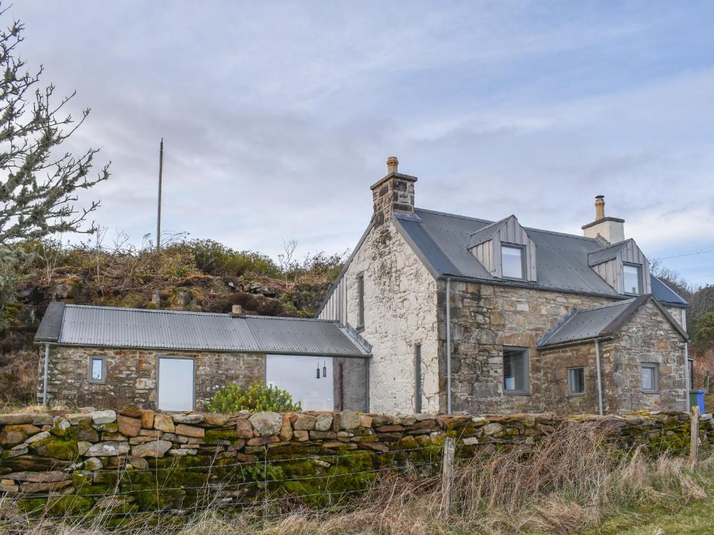 une ancienne maison en pierre avec un mur en pierre dans l'établissement Stone Cottage, à Elgol