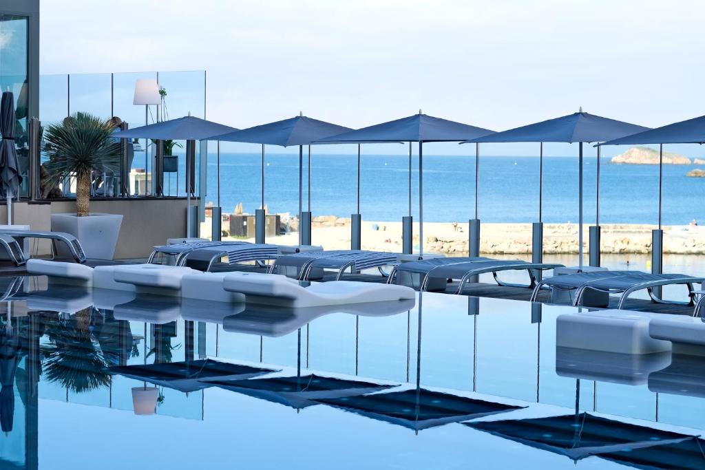a swimming pool with chairs and umbrellas at Thalazur Bandol Ile Rousse - Hôtel & Spa in Bandol