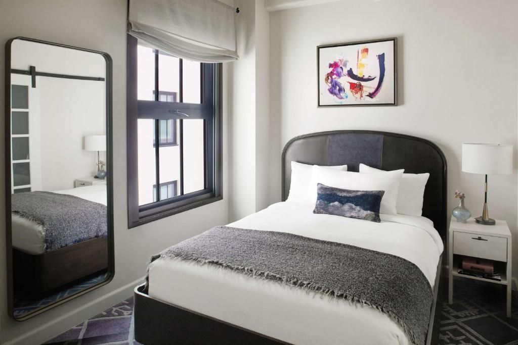 a bedroom with a bed and a mirror at Hotel Figueroa, Unbound Collection by Hyatt in Los Angeles