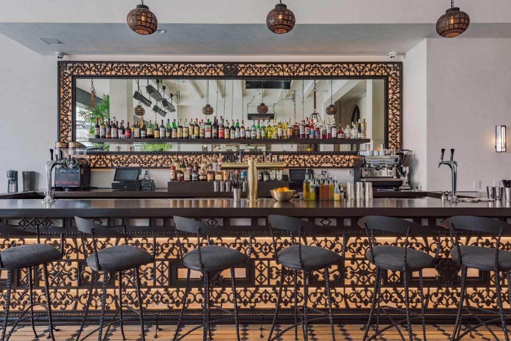 a bar with bar stools in front of a mirror at Hotel Figueroa, Unbound Collection by Hyatt in Los Angeles