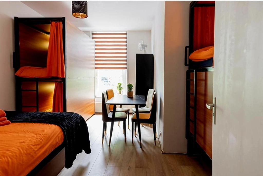 een slaapkamer met een tafel en stoelen en een bed bij Recharge Hostel in Rotterdam