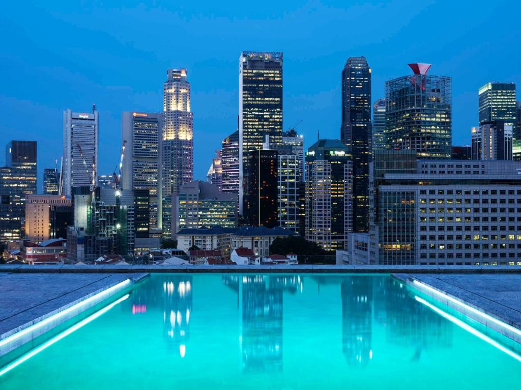 a view of a city skyline at night from a swimming pool at Mondrian Singapore Duxton in Singapore