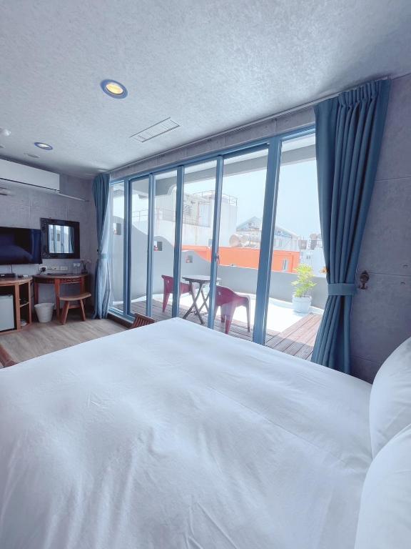 a bedroom with a white bed and a large window at Blue Sea Inn in Eluan