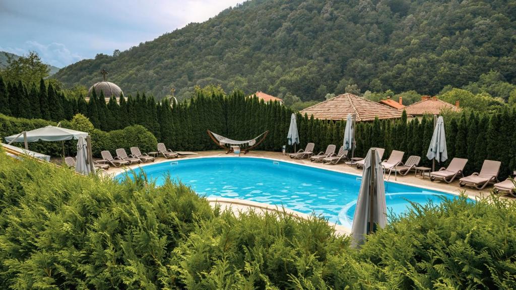 a swimming pool with chairs and umbrellas at Chalet Balkan in Valevtsi