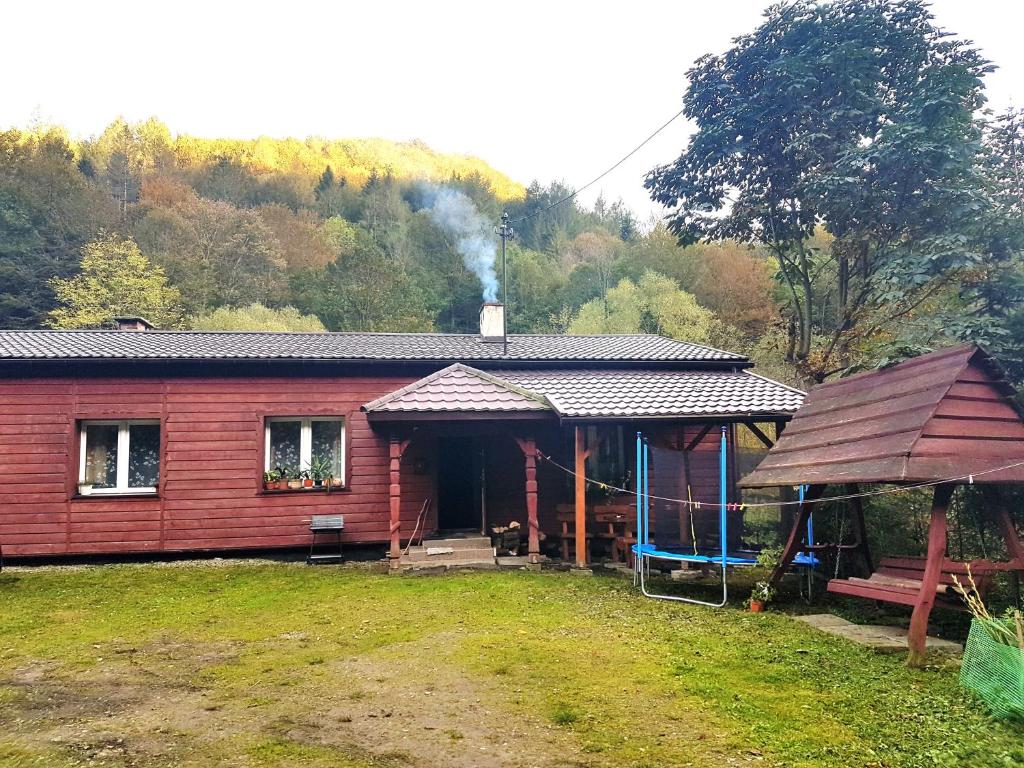 Noclegi u Barbary في Nasiczne: منزل احمر صغير مع شرفة