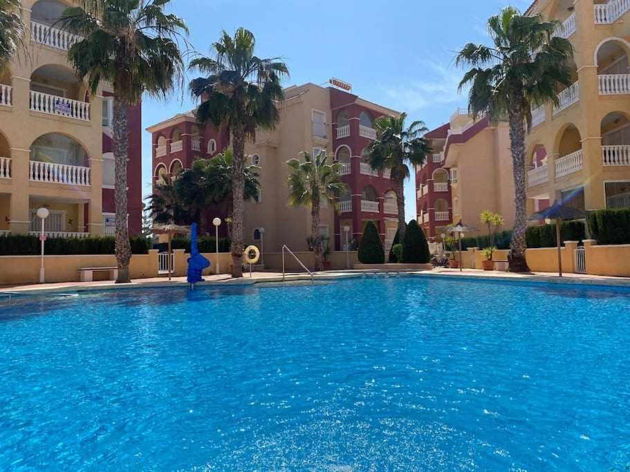 een groot zwembad voor een gebouw bij Acogedor apartamento cerca de la playa in Los Alcázares