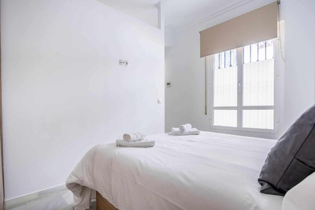 biała sypialnia z łóżkiem i ręcznikami w obiekcie COMFY AWAY - Apartamento Deluxe Centro Histórico w Sewilli