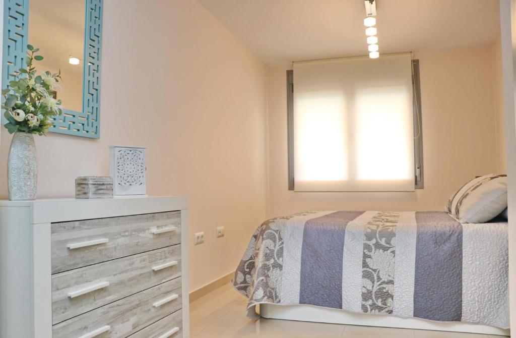 1 dormitorio con cama, tocador y espejo en Apartamento Puerta del Sol, en Conil de la Frontera