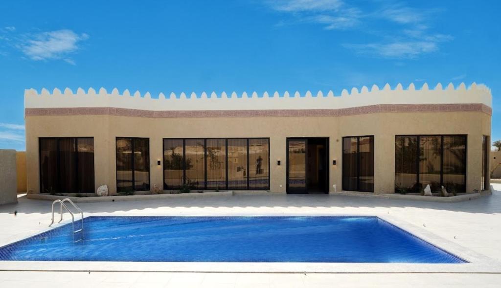 a large swimming pool in front of a building at Sidra Resort in Buqayq